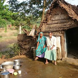 Beneficiary sitting in front of their damaged house due to heavy rain